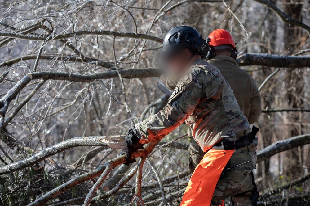 Georgia State Defense Force crew cutting through ice-coated fallen branches in White County, Georgia, during Winter Storm Fern.